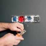 Crop faceless electrician using pliers for installation sockets and switches in new apartment