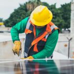 Professional solar panel technician working outdoors with PPE.